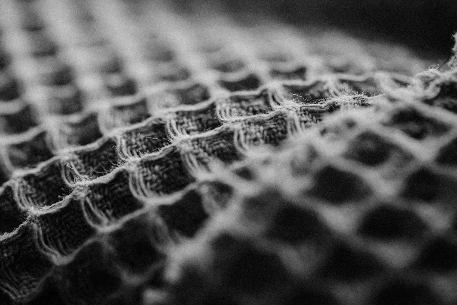 Detailed black and white close-up of a textured fabric weave pattern, artistic and abstract.
